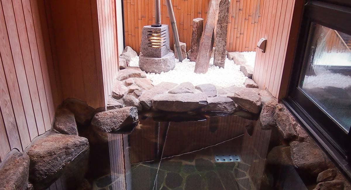 Natural stone bath with white pebble rock garden and bamboo at Oyado Koto no Yume, Takayama