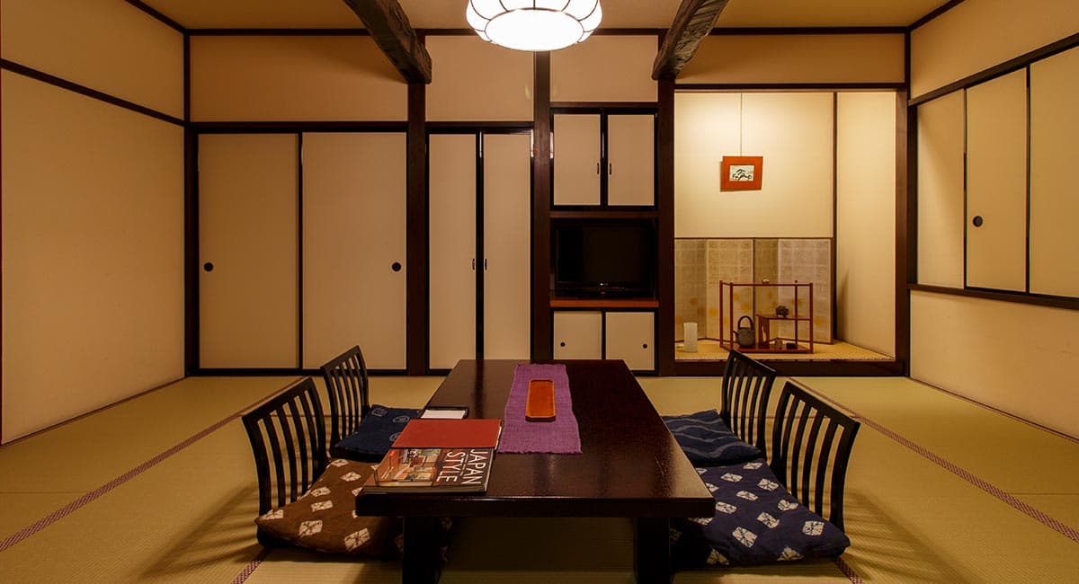 Traditional tatami guest room with low dining table, floor cushions and tokonoma alcove at Oyado Koto no Yume in Takayama