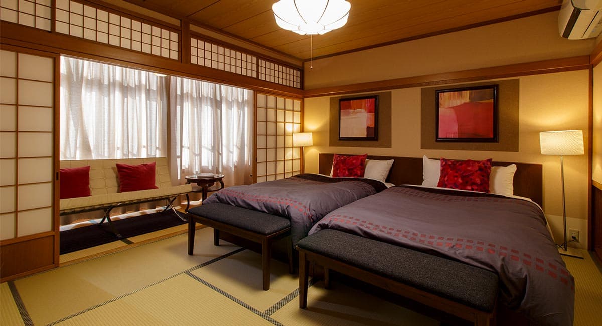 Japanese-Western twin-bed guest room with tatami floor, shoji screens and window bench at Oyado Koto no Yume in Takayama