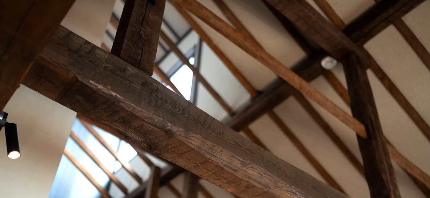 Yubatake Sensui annex interior architecture, exposed dark timber beams and rafters with a skylight, in the historic Naraya building