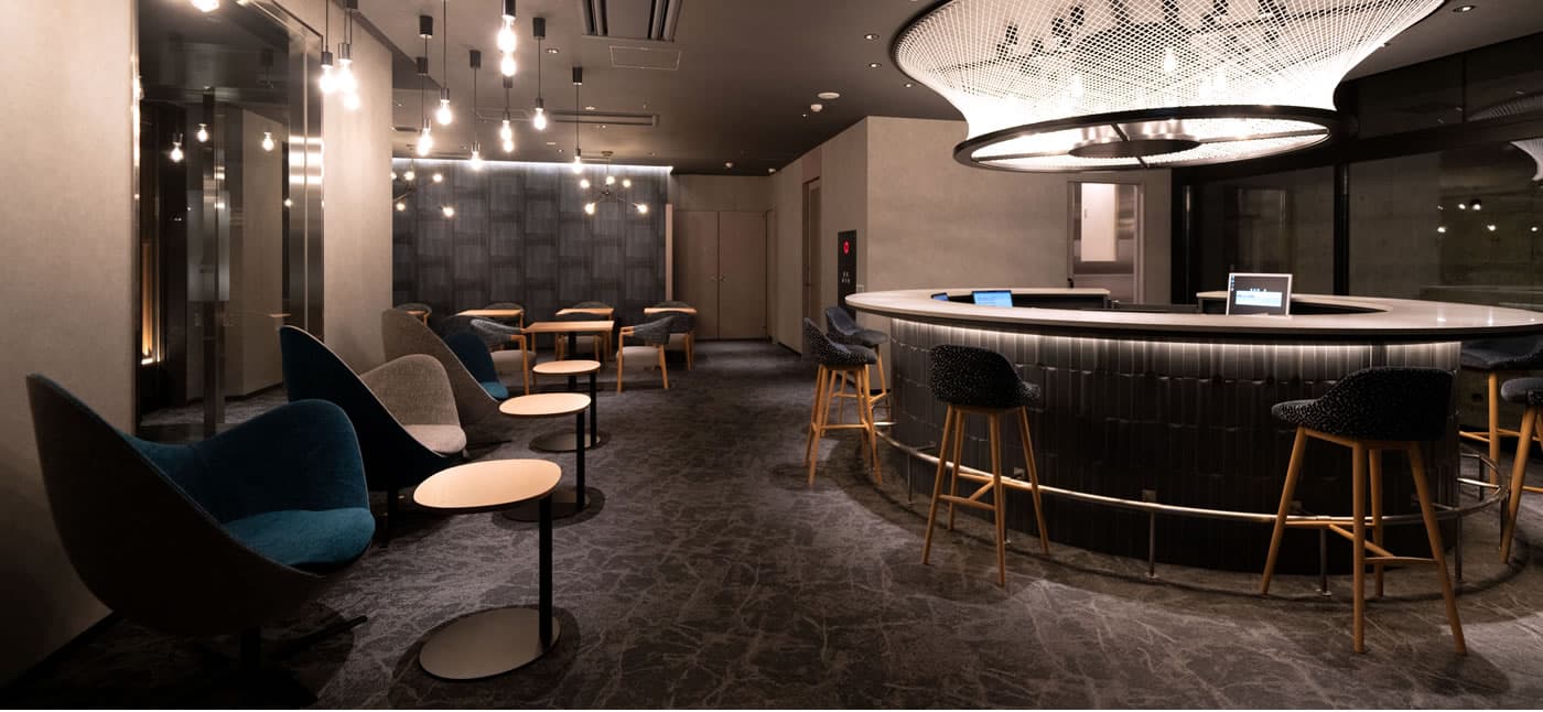 Yubatake Sensui lounge bar with a curved counter, high stools, modern armchairs and a ring chandelier