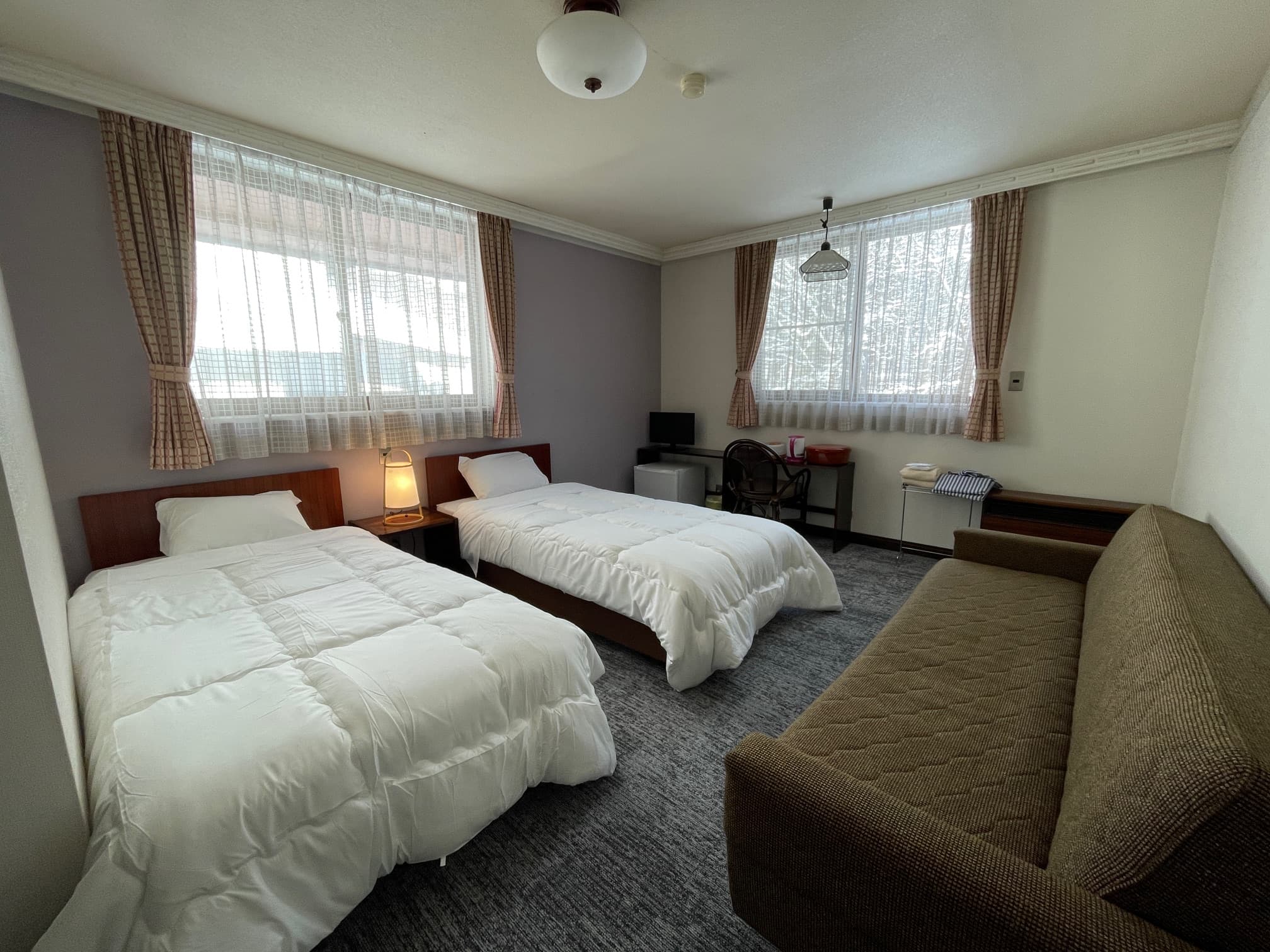 Western-style twin bedroom with sofa and large windows at Matsunoki-tei in Hakuba