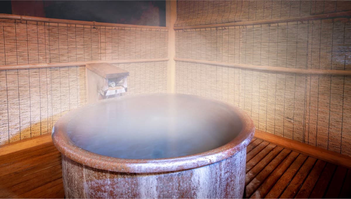 Round private cypress soaking tub wreathed in steam inside a reed-walled bath room at Meitoya So