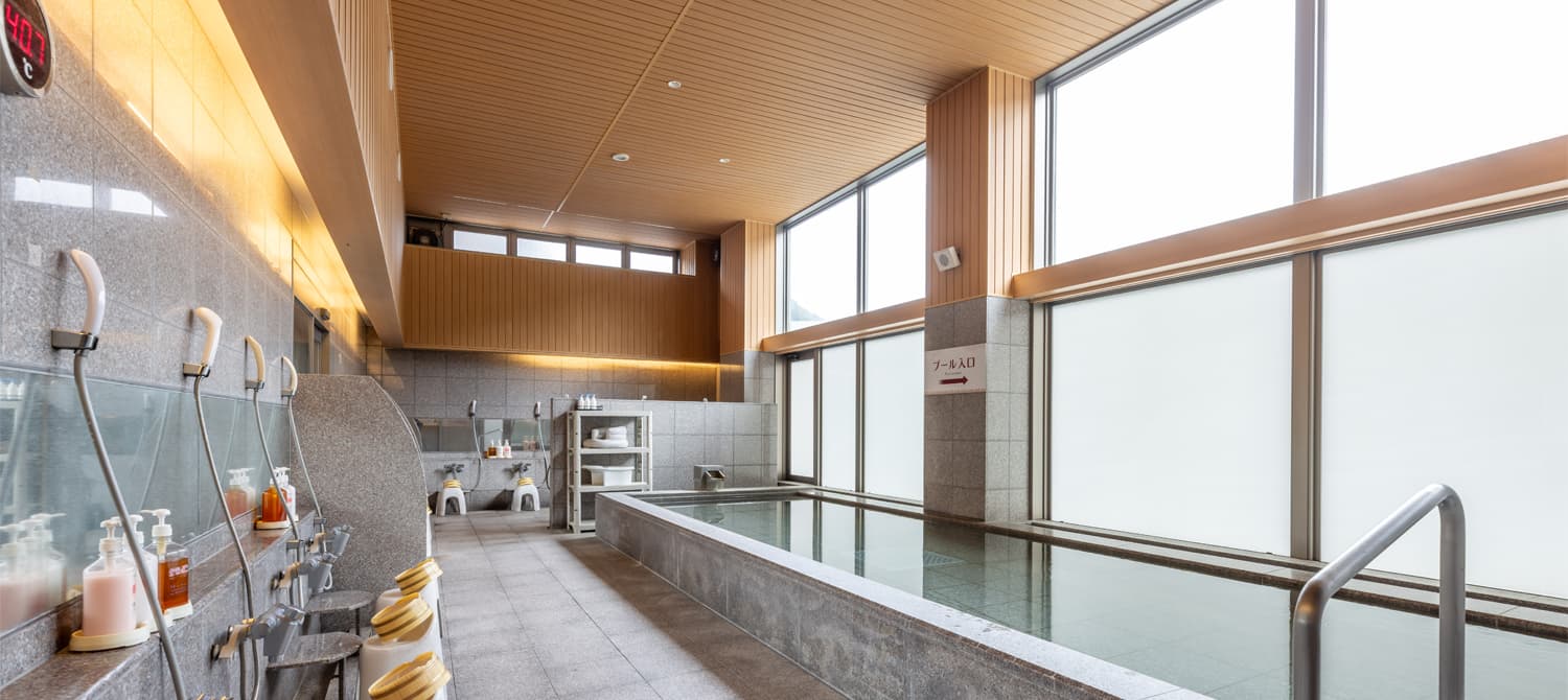 Indoor hot spring bath with washing stations and tall windows