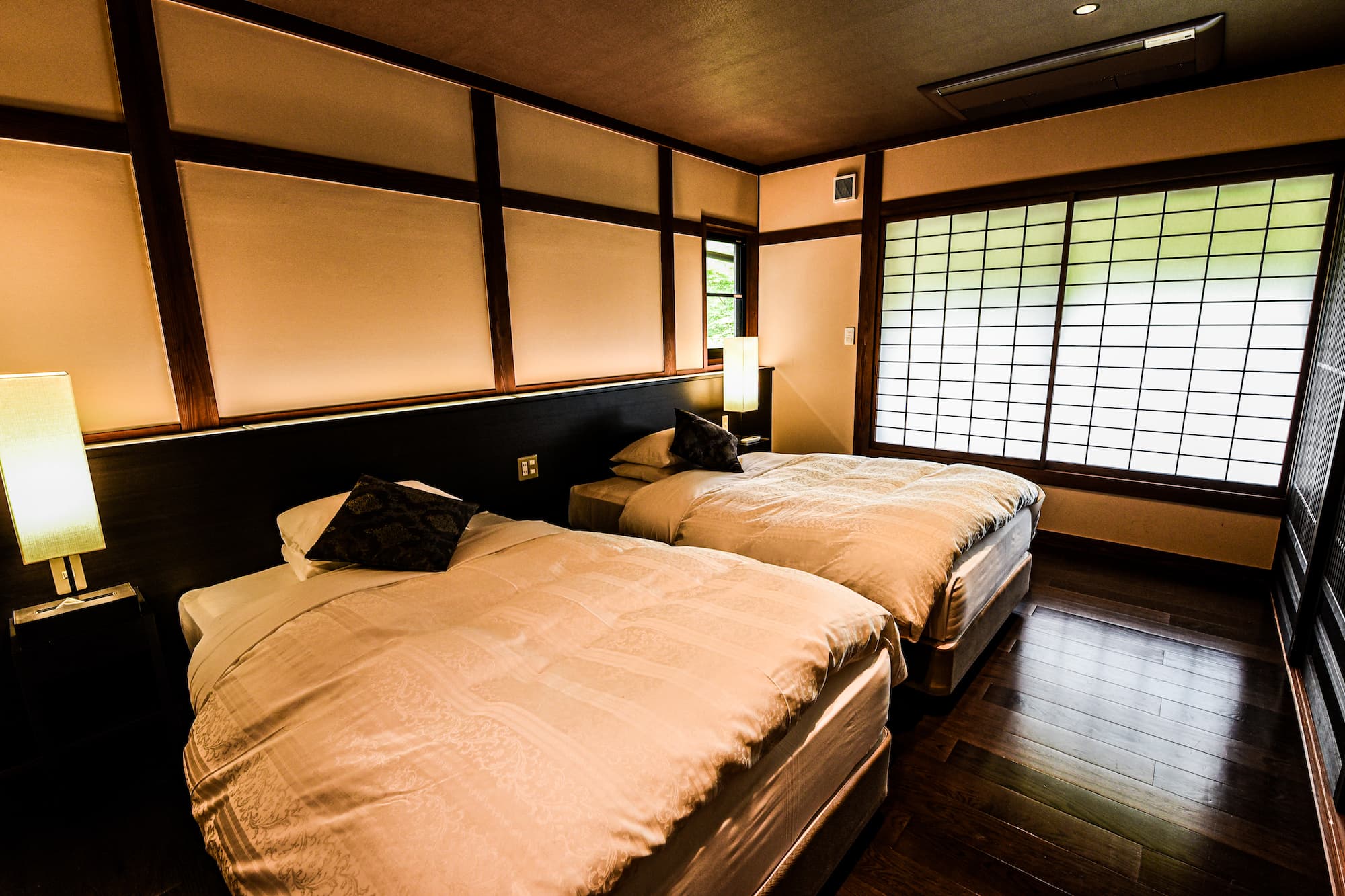 Twin-bed guest room with shoji-screened windows, dark timber framing and warm lamplight