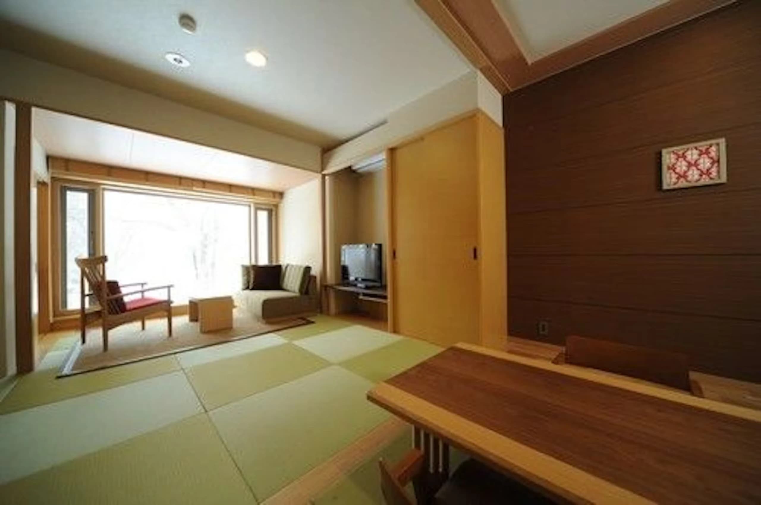 Japanese-style tatami guest room with low table, lounge chairs and a wide window onto the forest at Oku Nikko Mori no Hotel