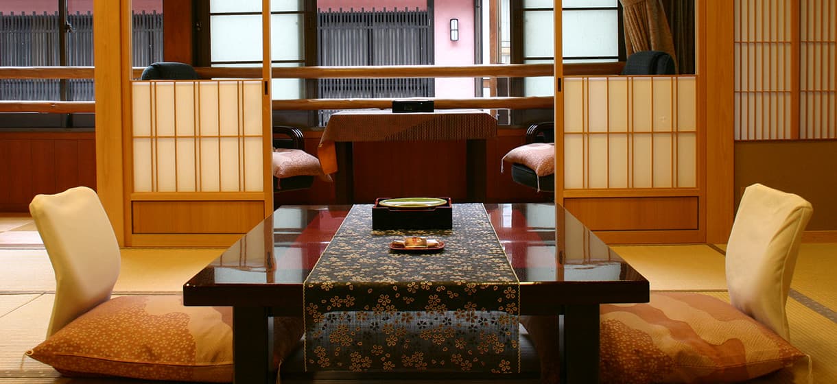 Spacious tatami guest room at Morizuya with low lacquer table, floor cushions and round bamboo-latticed window