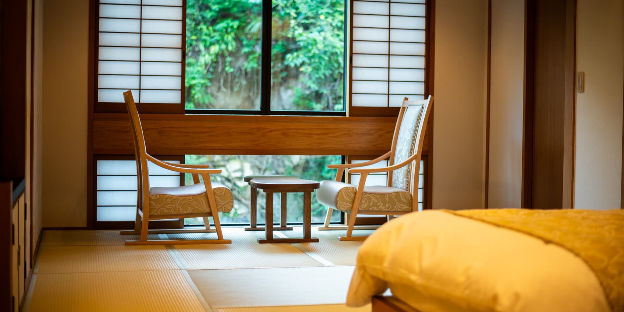Tatami guest room at Nansuikaku with shoji screens, paired armchairs and a garden view window