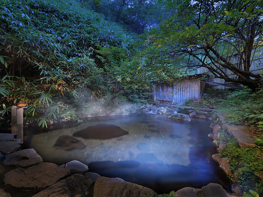 Misty natural rock river bath among bamboo and greenery