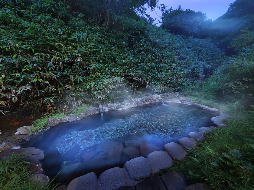 Stone-lined natural river hot-spring pool in the forest