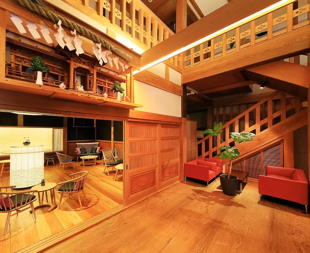 Warm wooden two-story lobby lounge with red sofas and traditional joinery at Fuji Onsenji Yumedono