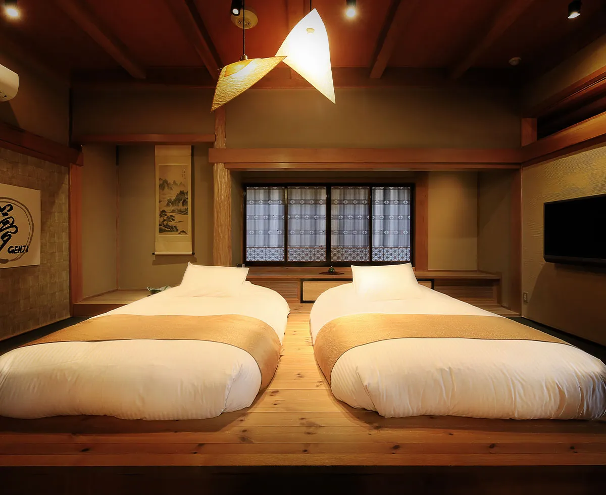 Japanese-style guest room at Fuji Onsenji Yumedono with futon bedding on a raised cedar platform, hanging-scroll alcove and paper lanterns
