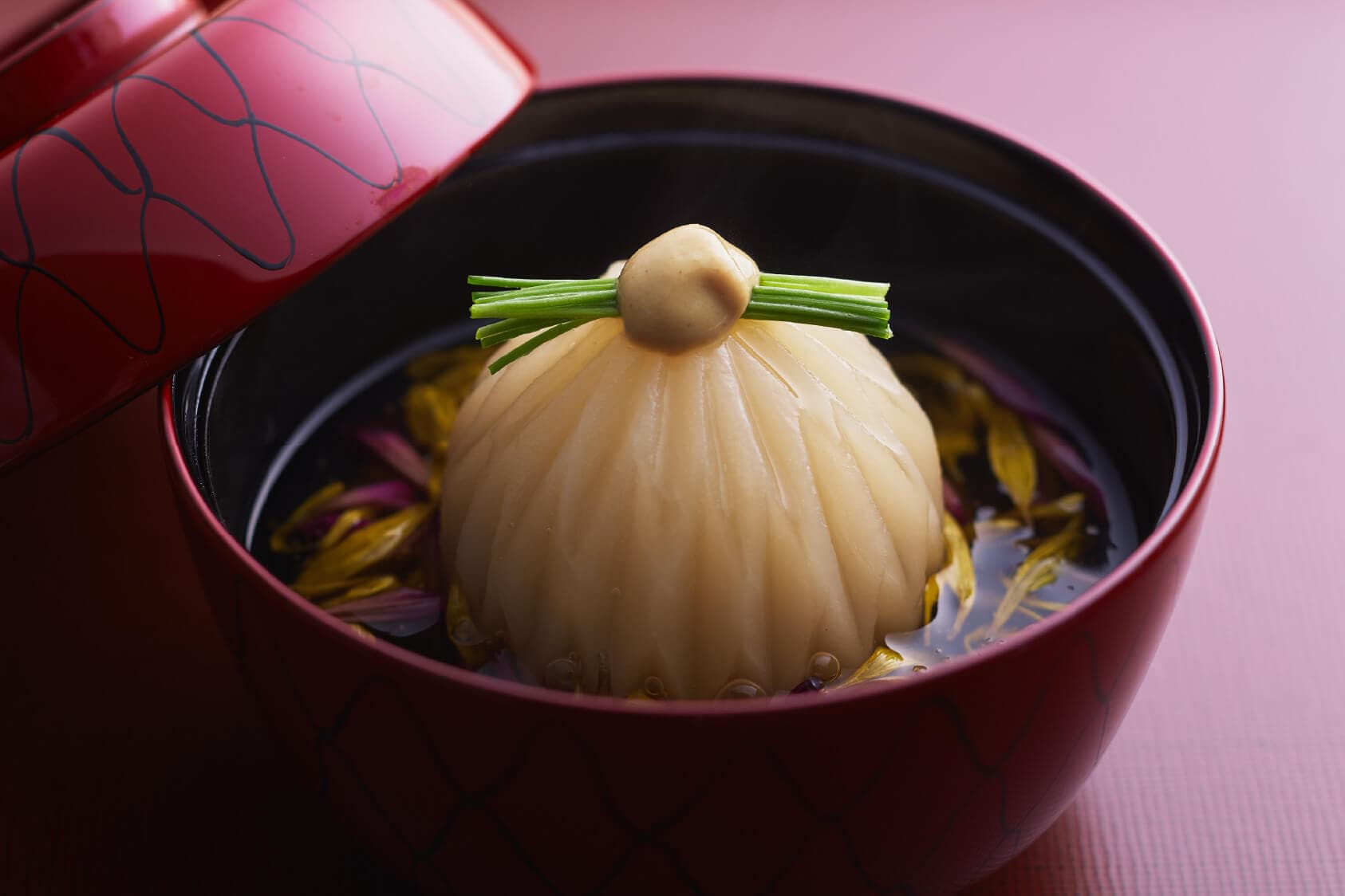 Clear soup course at Tsuchiya, a delicate turnip dumpling garnished with greens in a red lacquer lidded bowl