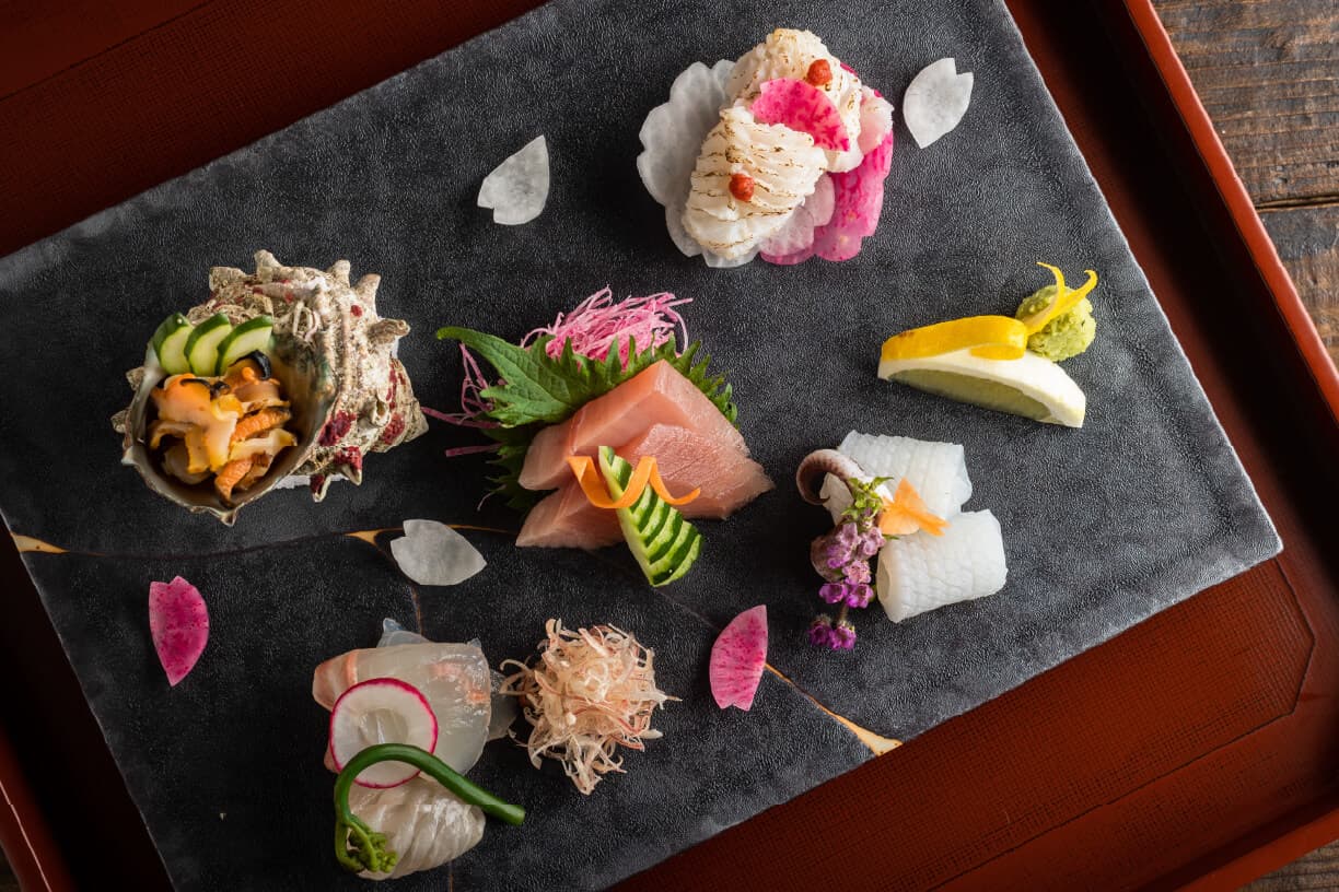 Assorted kaiseki appetizers at Tsuchiya artfully plated on slate over a red lacquer tray