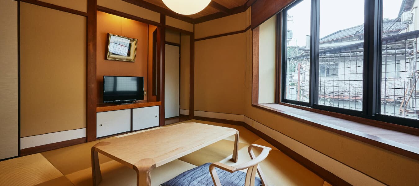 Compact tatami room at Tsuchiya with a low wooden table and corner window over the onsen-town street