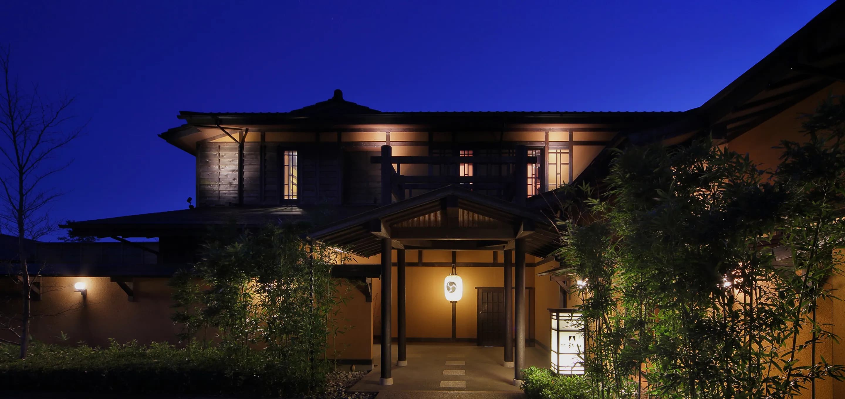 Oyado Uchiyama wooden entrance gate and lantern-lit approach at dusk in Izu, Shizuoka