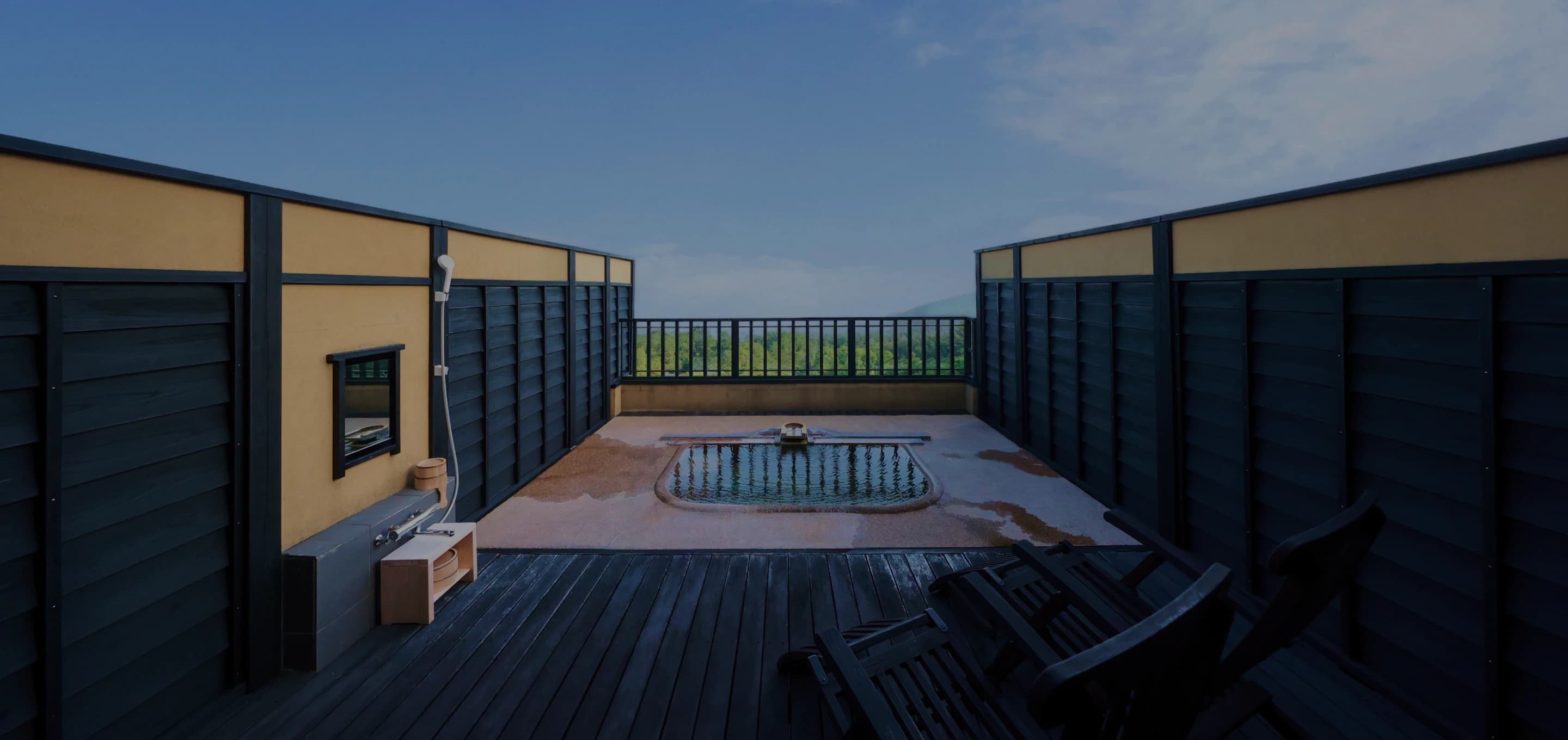 Open-air rooftop bath on a wooden deck at Oyado Uchiyama overlooking the surrounding Izu landscape
