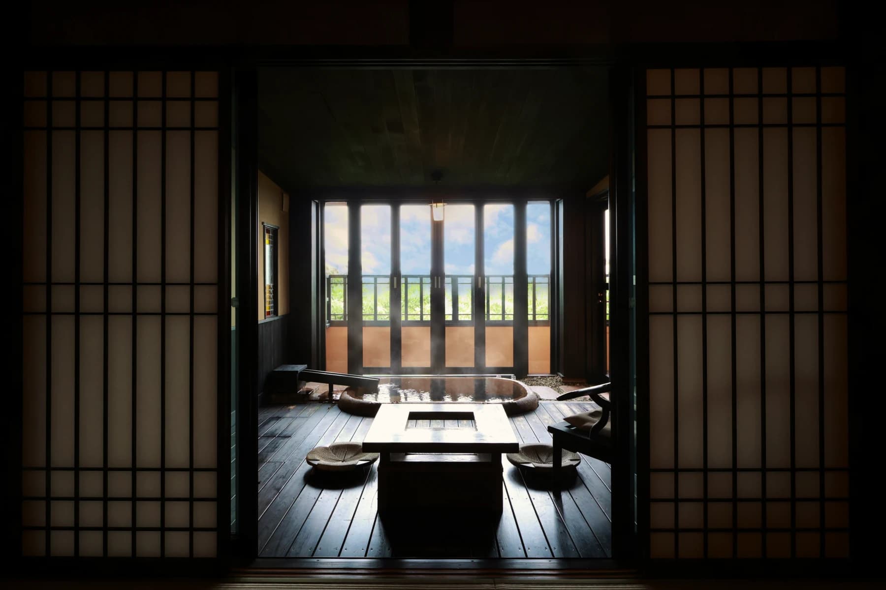 Atmospheric guest room at Oyado Uchiyama framed by shoji screens with an in-room hot-spring bath and low wooden table