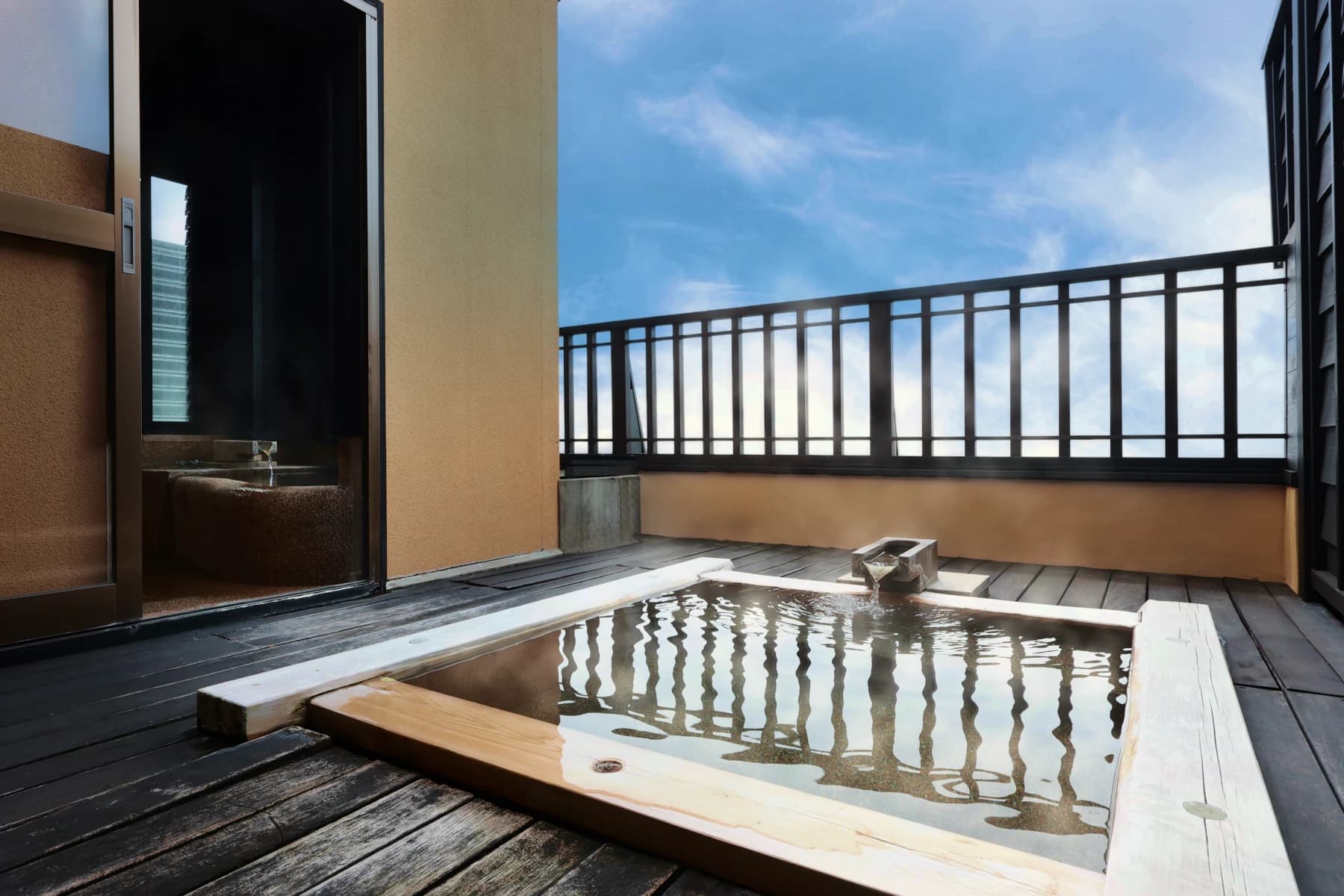 Private rooftop open-air hot-spring bath at Oyado Uchiyama with steaming water and clear blue sky in Izu