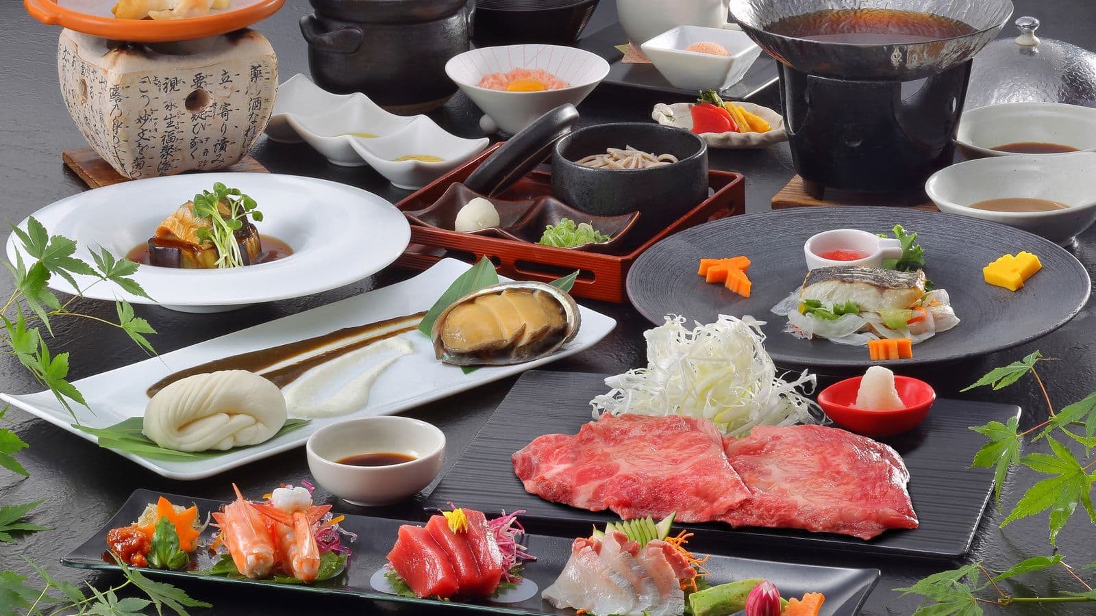 Multi-course kaiseki dinner spread with Hida beef, sashimi and abalone on black lacquer tableware at Ryu Resort and Spa