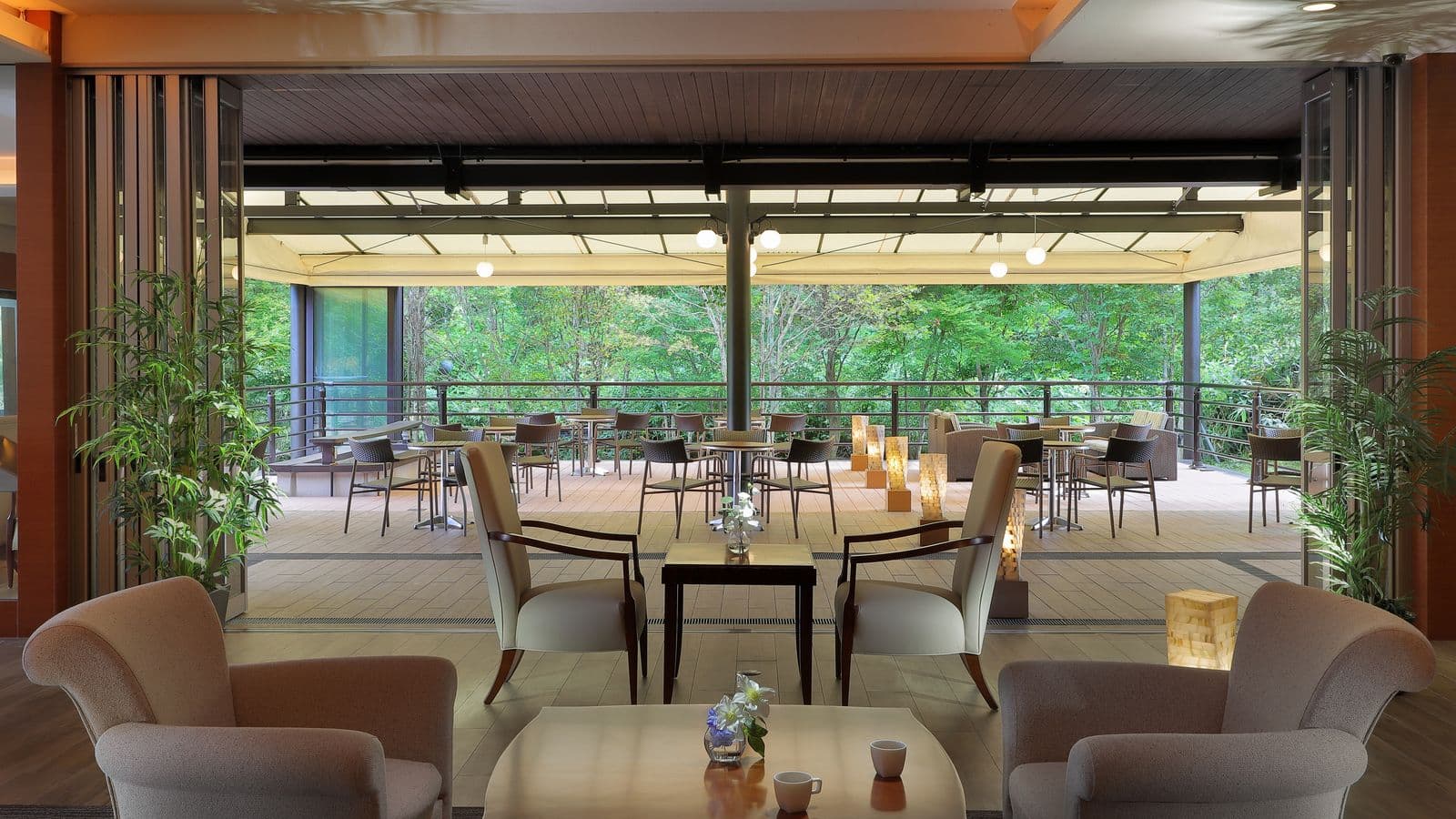 Open lounge with armchairs leading to an open-air terrace cafe surrounded by greenery at Ryu Resort and Spa near Takayama