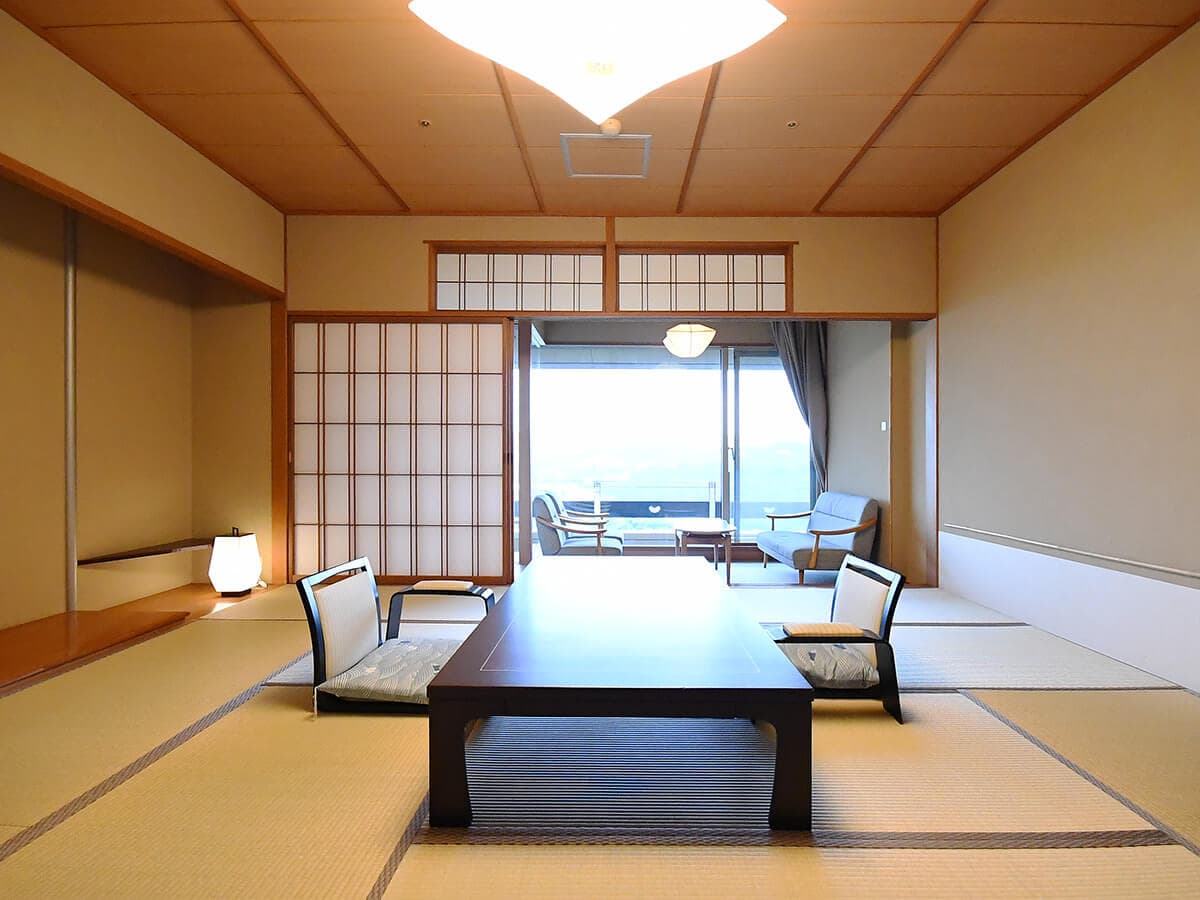 Japanese-style tatami guest room with armchairs and a sea-facing balcony at Seizan Yamato, Izu