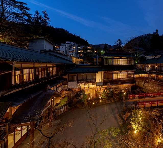 積善館 夕暮れの館内全景と灯された朱塗りの橋 © sekizenkan.co.jp