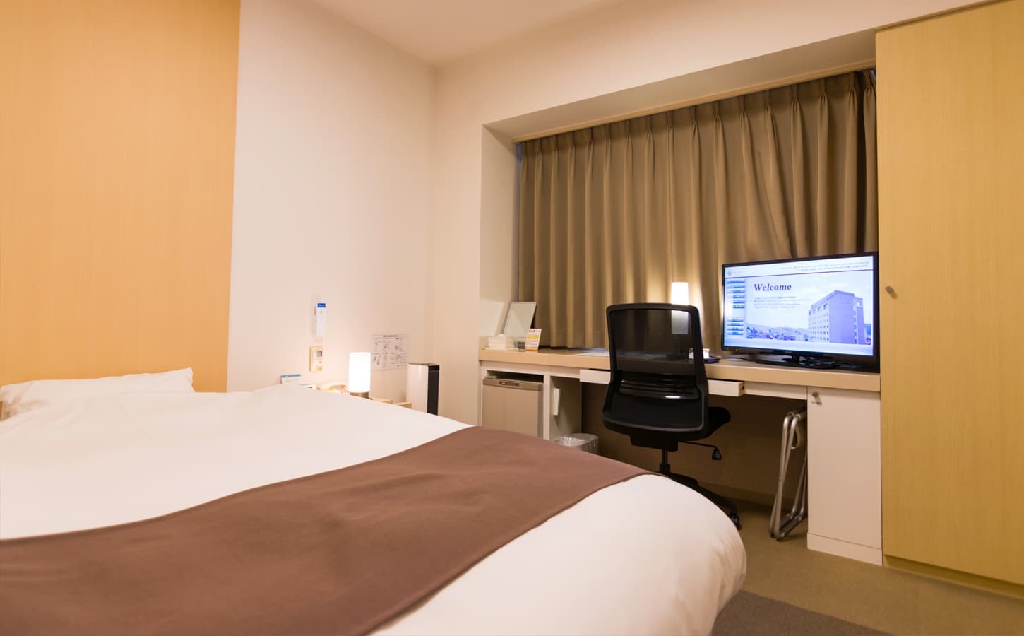 Single guest room at Spa Hotel Alpina with a wide bed, desk and curtained window