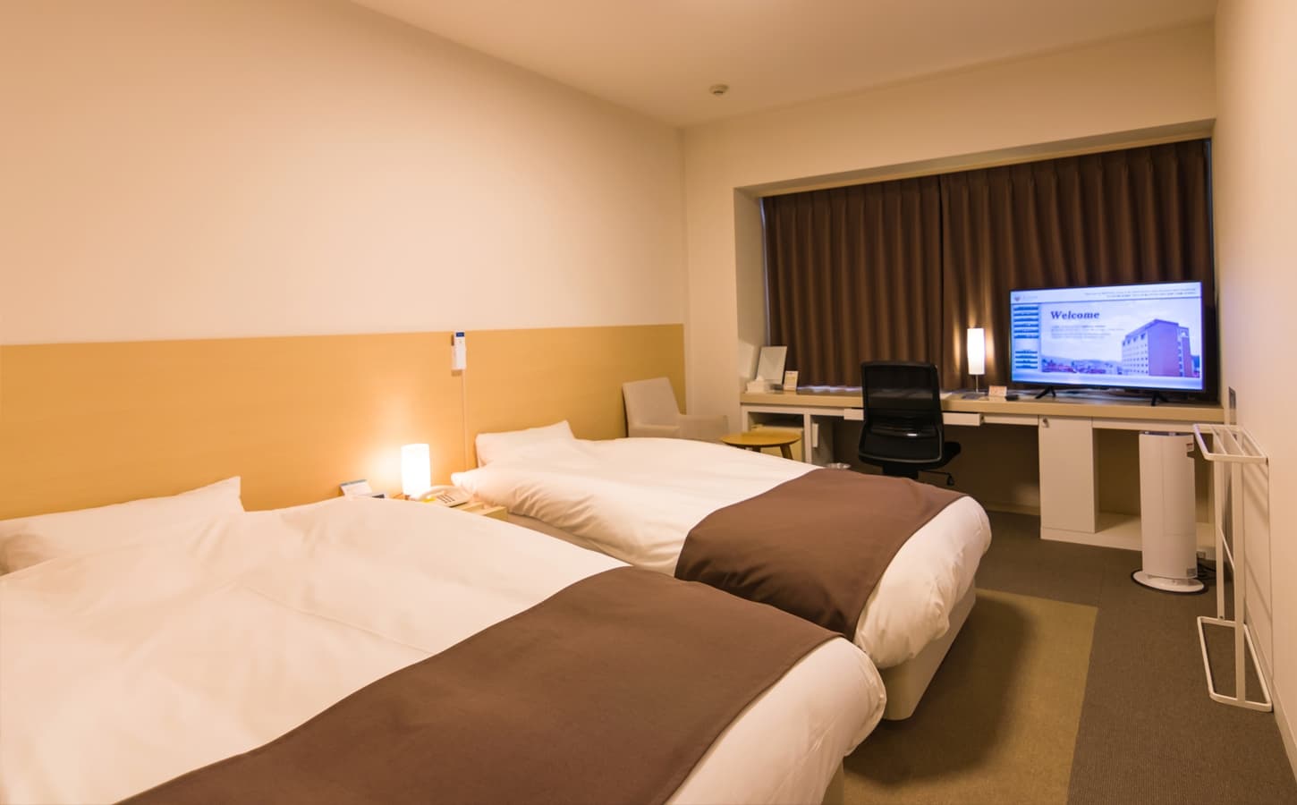 Standard twin guest room at Spa Hotel Alpina with two beds, a work desk and warm wood-toned walls