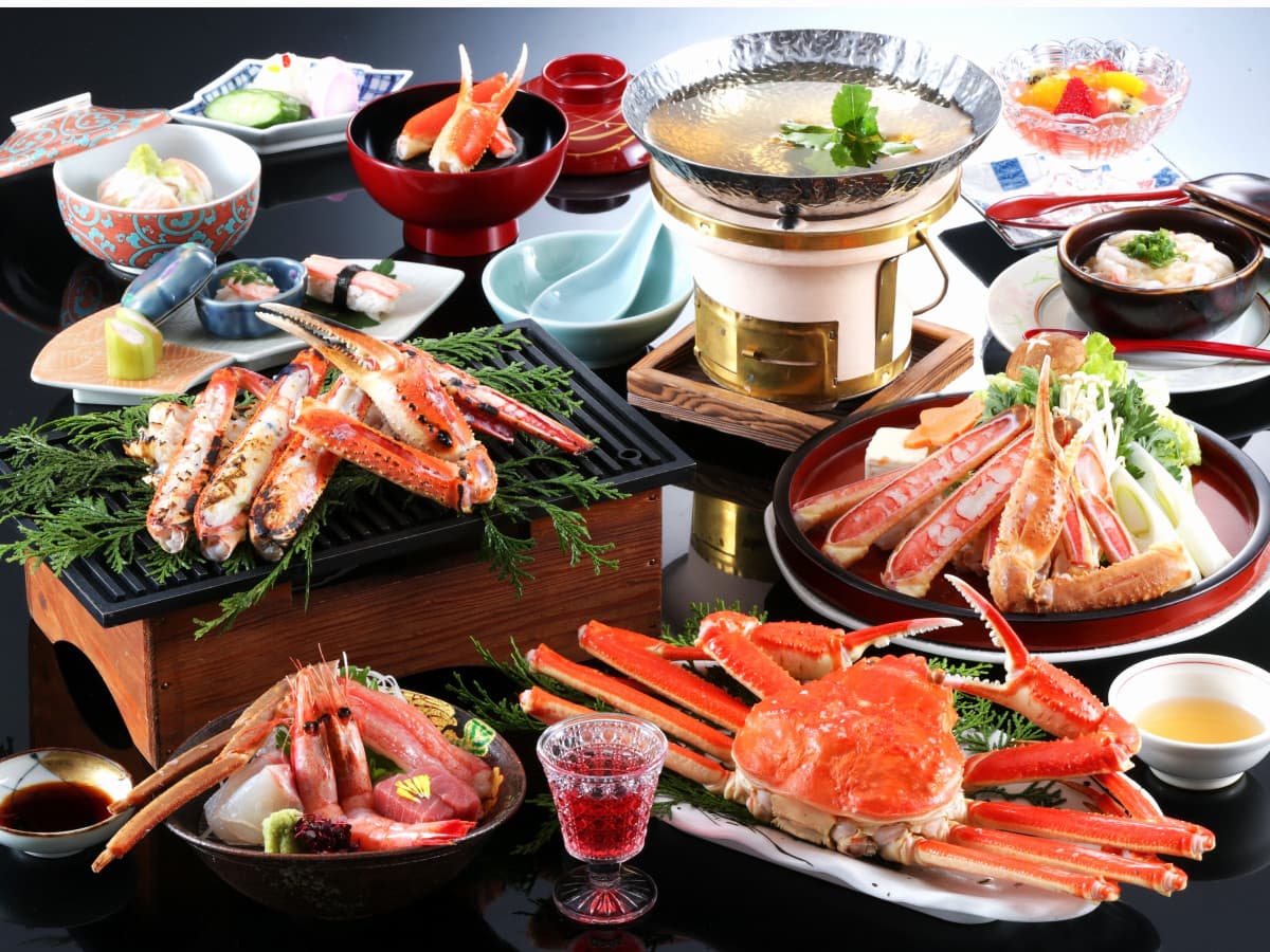 Full snow-crab kaiseki course with boiled crab, sashimi and tabletop hotpot on a black table, Onishiya Suishoen, Kinosaki Onsen