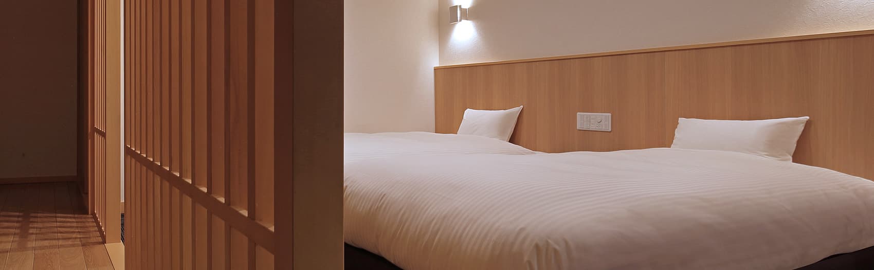 Modern Japanese guest room with twin beds, wood paneling and lattice screen at Hotel Sunshine Kinugawa, Kinugawa Onsen