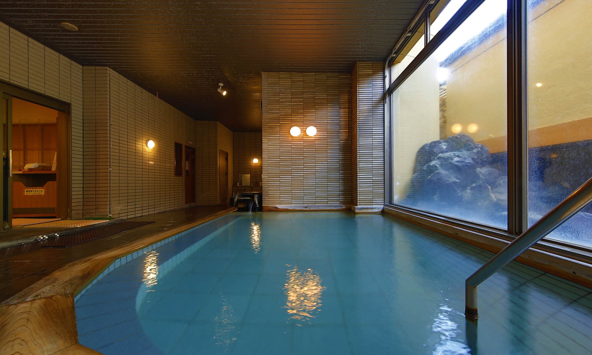 Large indoor tiled hot spring bath at Ibusuki Shusuien with garden window view
