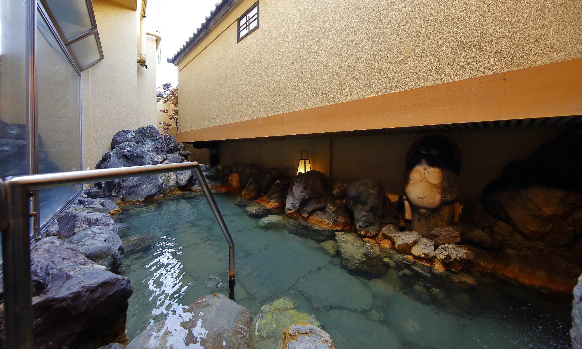 Rock-lined open-air hot spring bath (rotenburo) at Ibusuki Shusuien with stone lantern