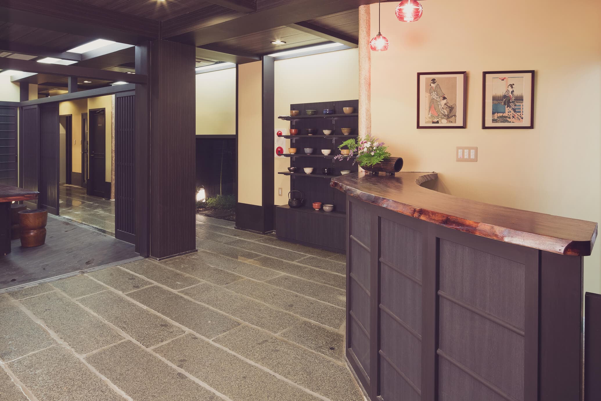 Reception area of The Edo Sakura with live-edge wood counter, stone-paved floor and ukiyo-e prints, Tokyo