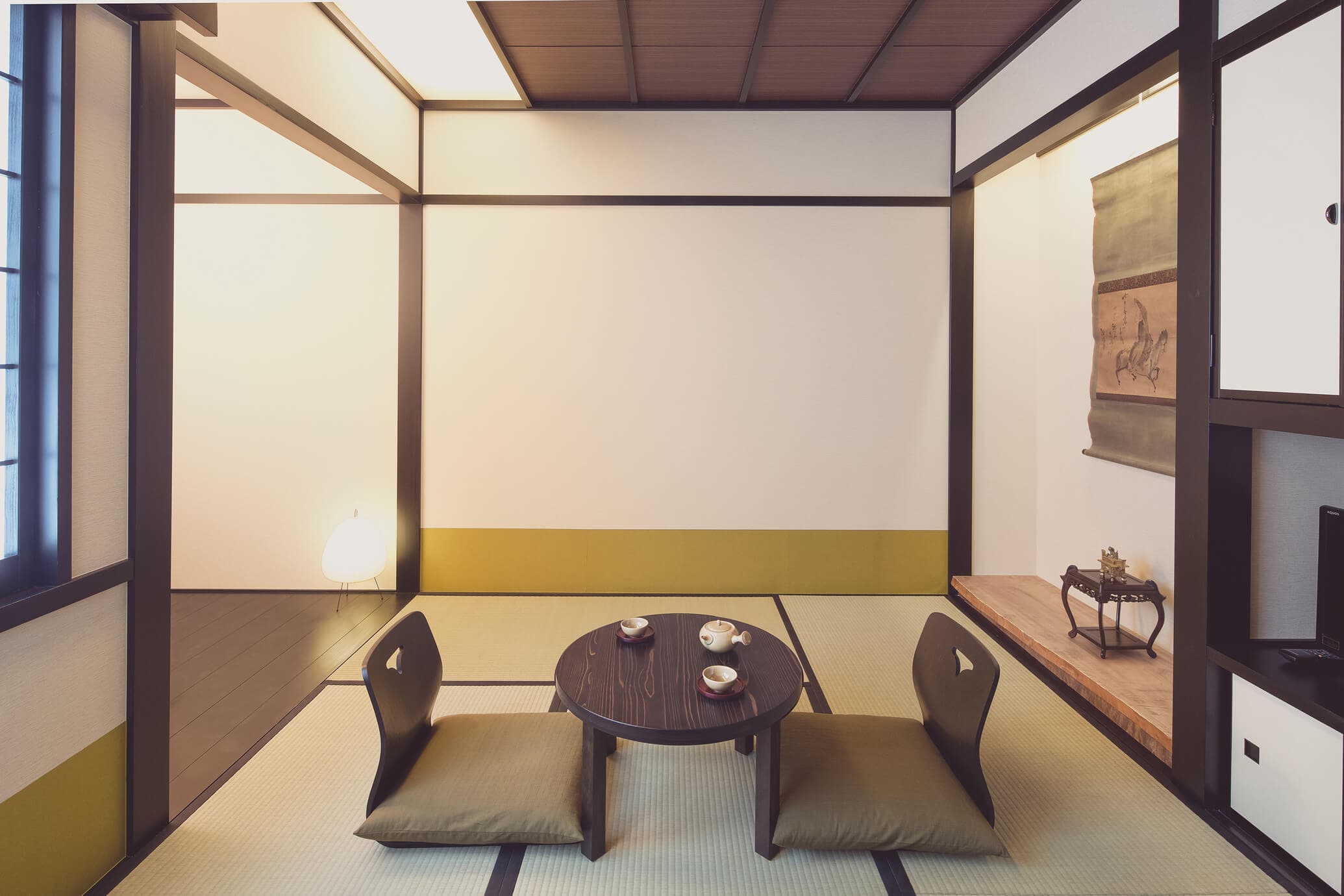 Tatami guest room at The Edo Sakura with low round table, floor chairs and hanging scroll, Tokyo