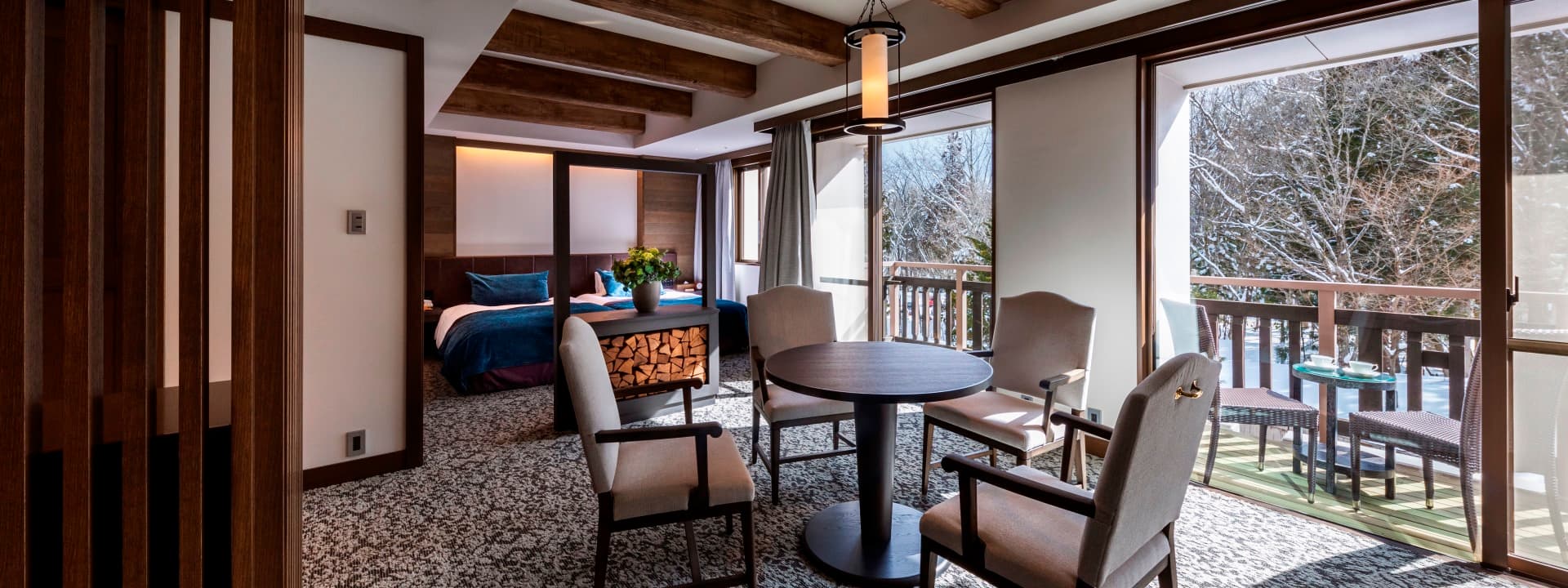 Japanese-style room at Hakuba Tokyu Hotel with low bed, lounge table and a balcony overlooking snowy woods