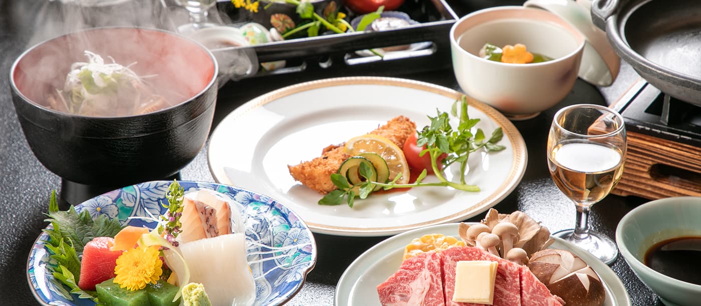 Kaiseki dinner spread with steaming dish, sashimi, fried fish and marbled wagyu beef hot pot