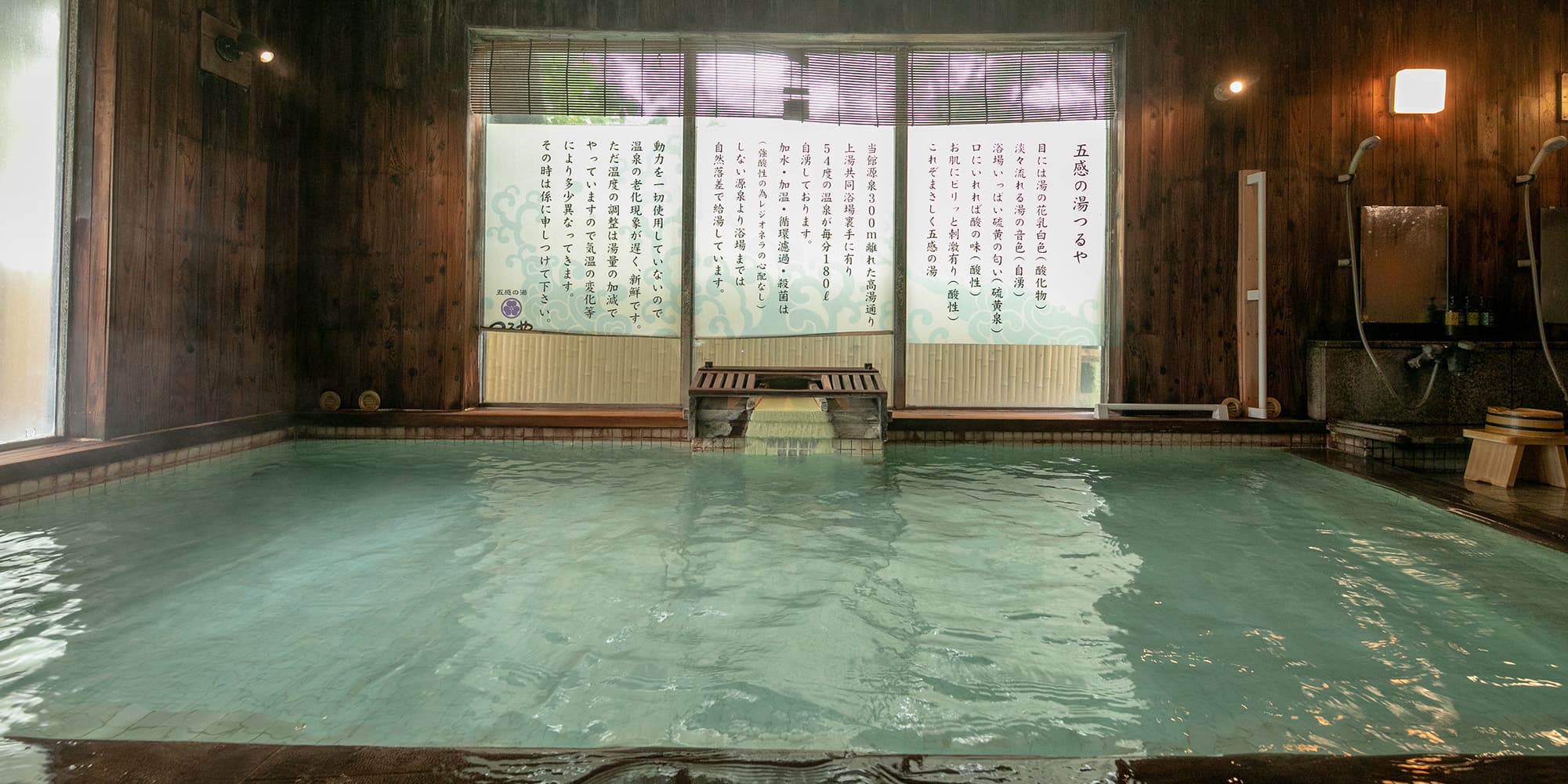 Indoor hinoki onsen bath filled with cloudy white sulfur spring water at Gokan no Yu Tsuruya