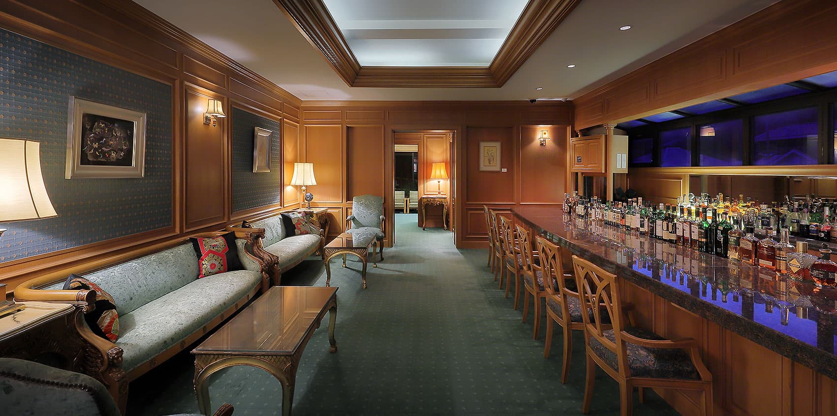 Wood-paneled lounge bar with antique sofas, table lamps and a long counter of bottles at Yagyu no Sho, Shuzenji Onsen, Izu