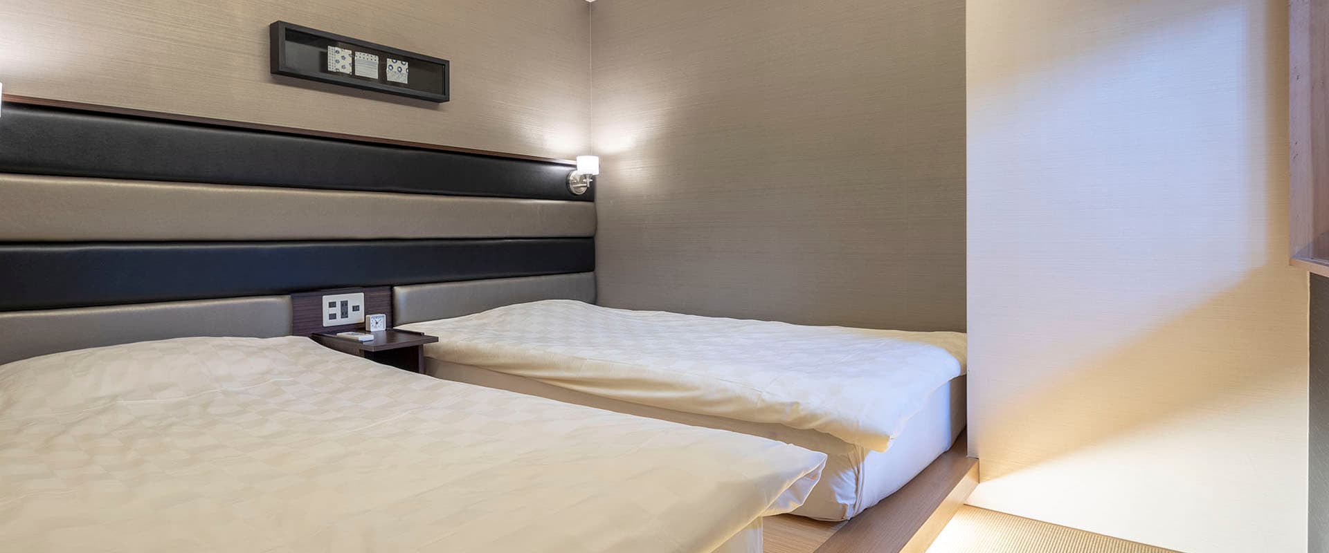 Modern twin-bed guest room with neutral tones, recessed lighting and a tatami-edge floor