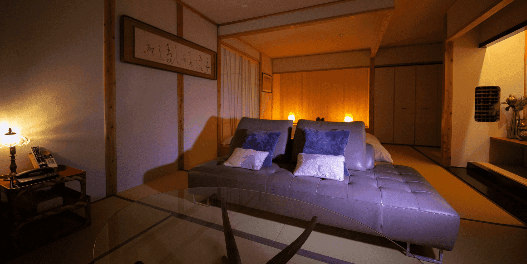 Evening guest room with a double bed, calligraphy panel and warm lamp lighting at Oyado Den Rikyu Yufuin