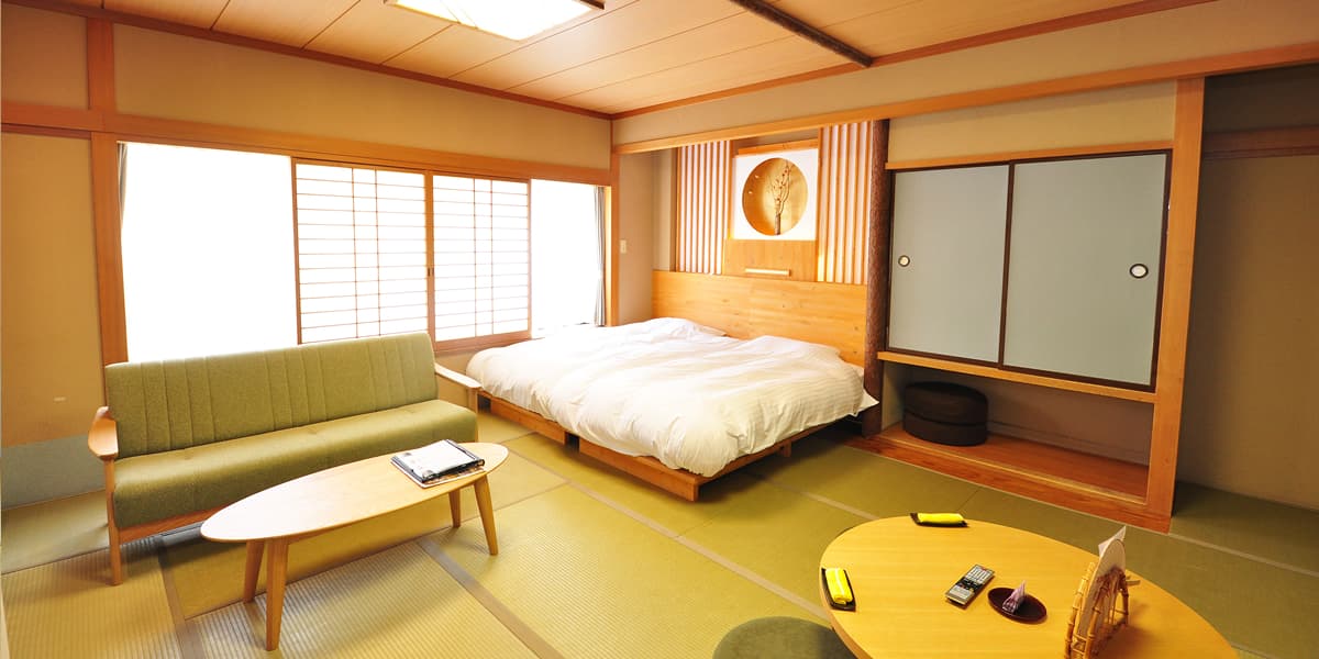 Tatami guest room with low wooden bed, sofa and alcove at Yumoto Itaya, Okunikko Yumoto Onsen