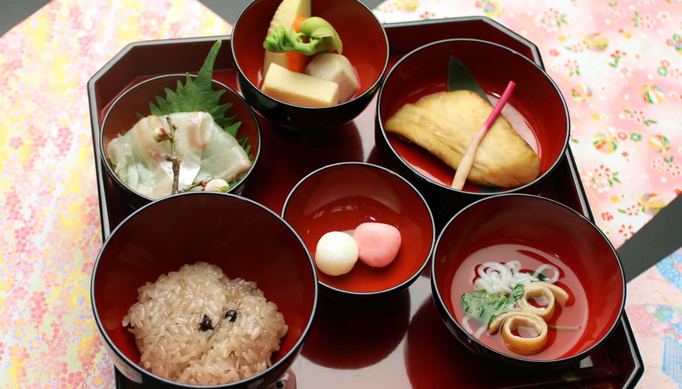 Japanese set meal served in stacked lacquer bowls on a floral tray at Yamaichi Bekkan, Miyajima
