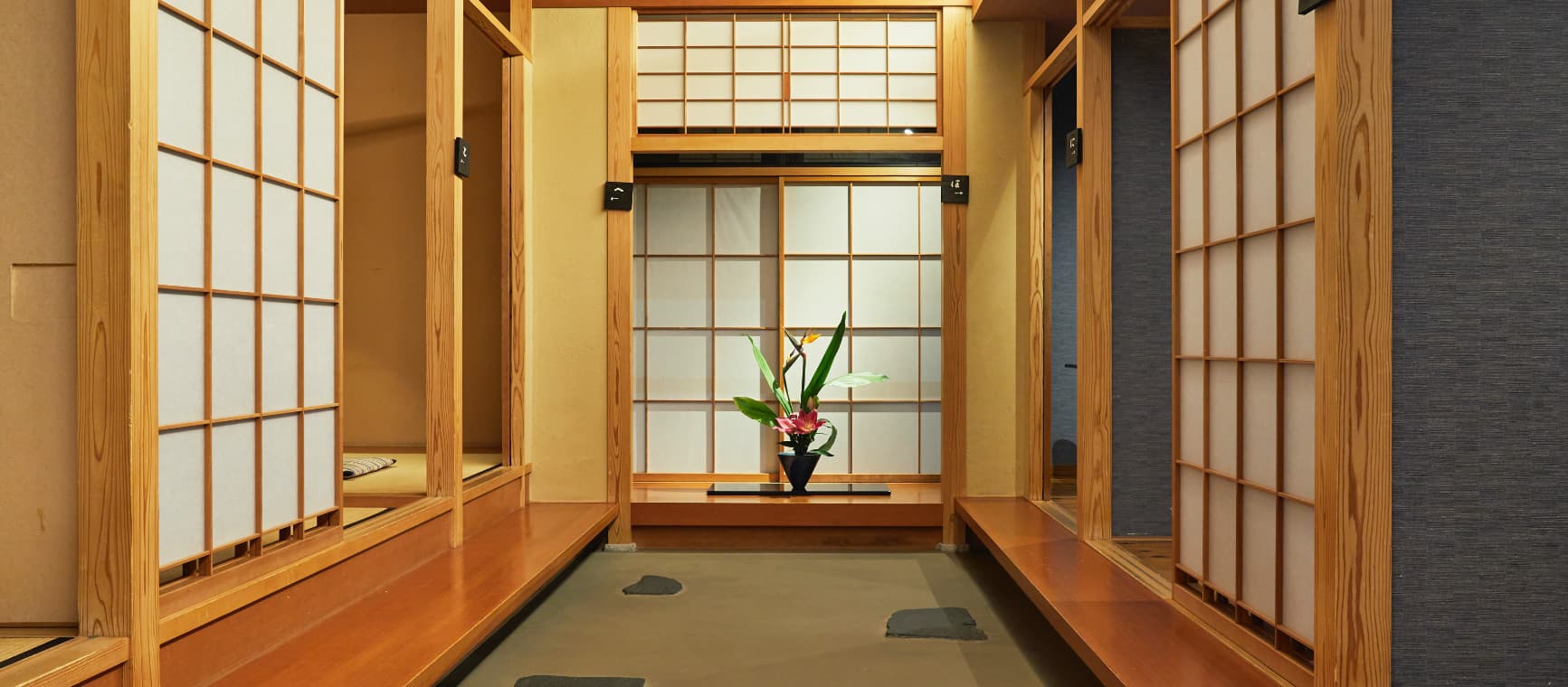 Interior corridor lined with paper screens and an ikebana arrangement