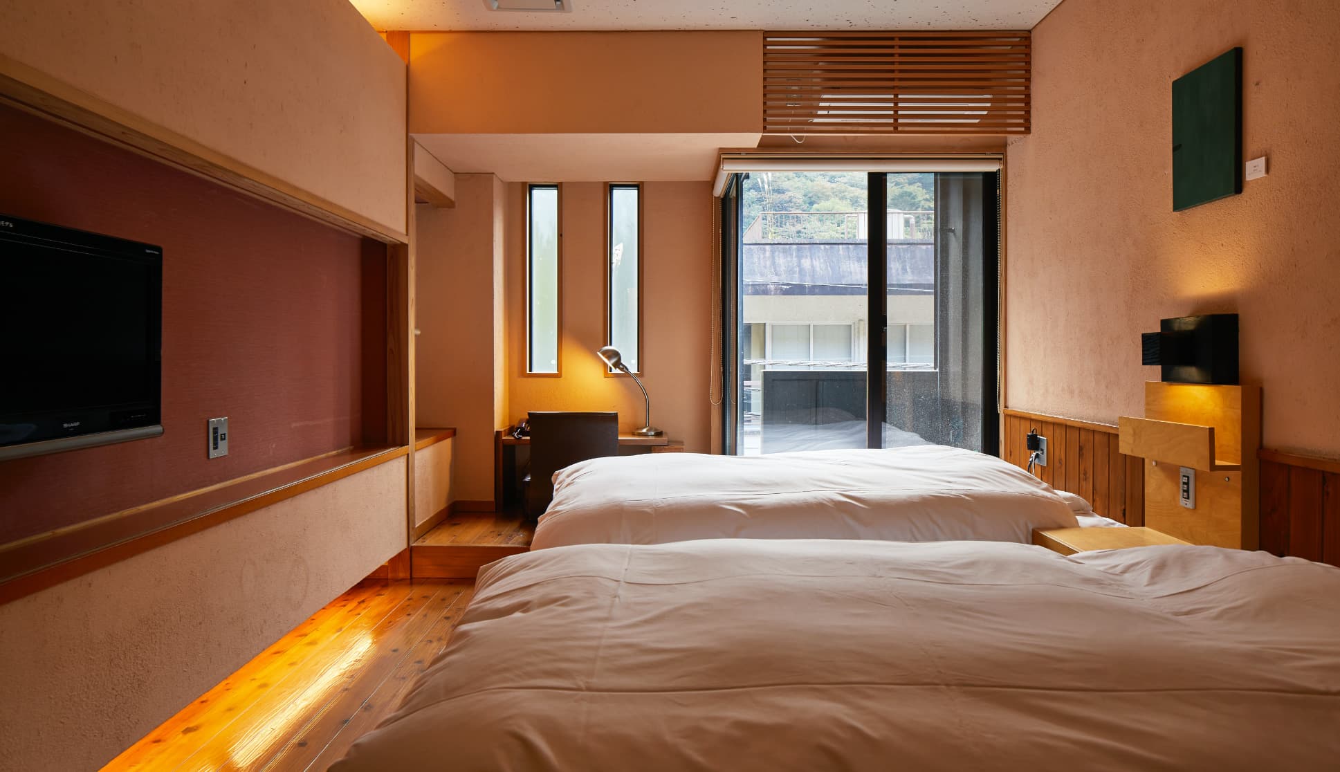 Minimalist guest room with twin beds, earthen walls and a mountain view