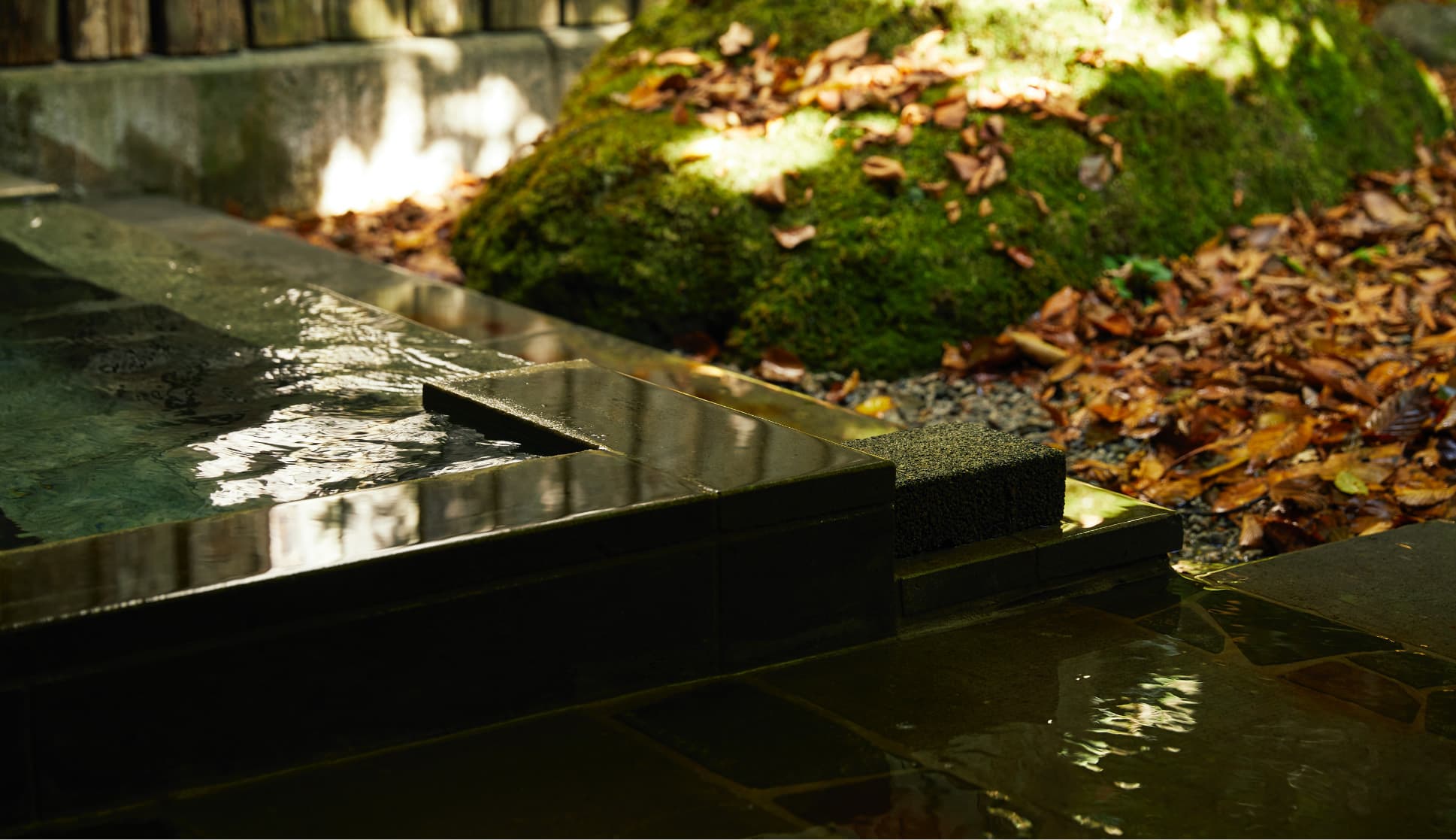 Stone-tiled indoor bath with a bamboo screen and forest view