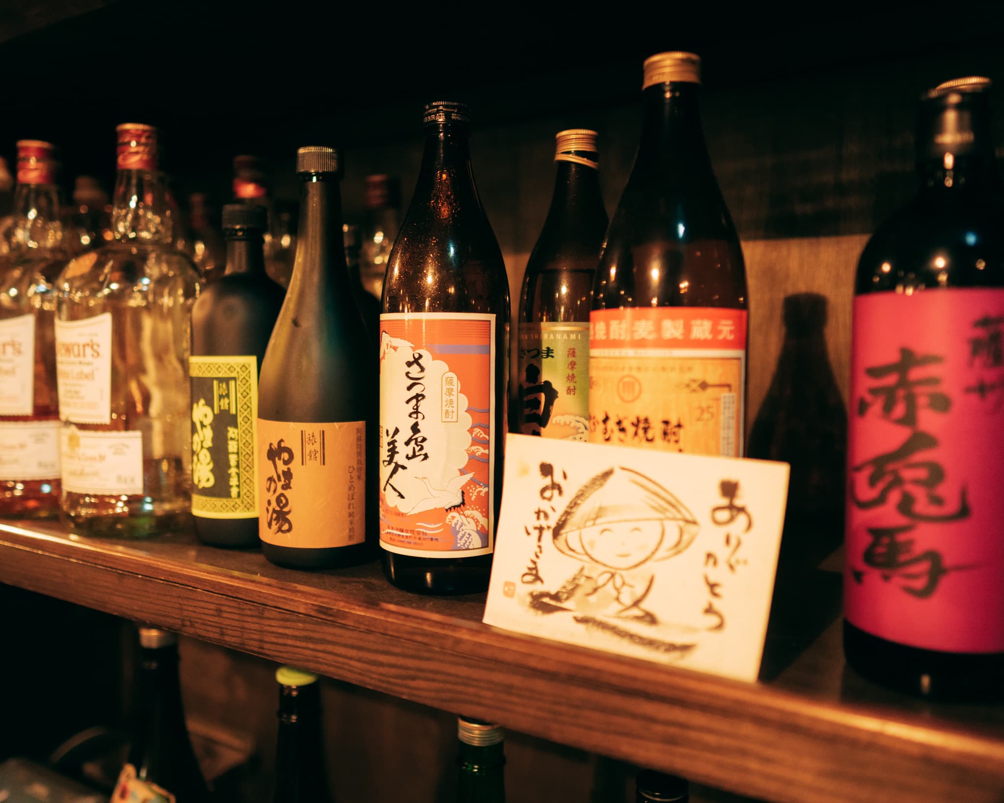 Ryokan Yamanoyu lounge bar shelf lined with regional shochu and whisky bottles