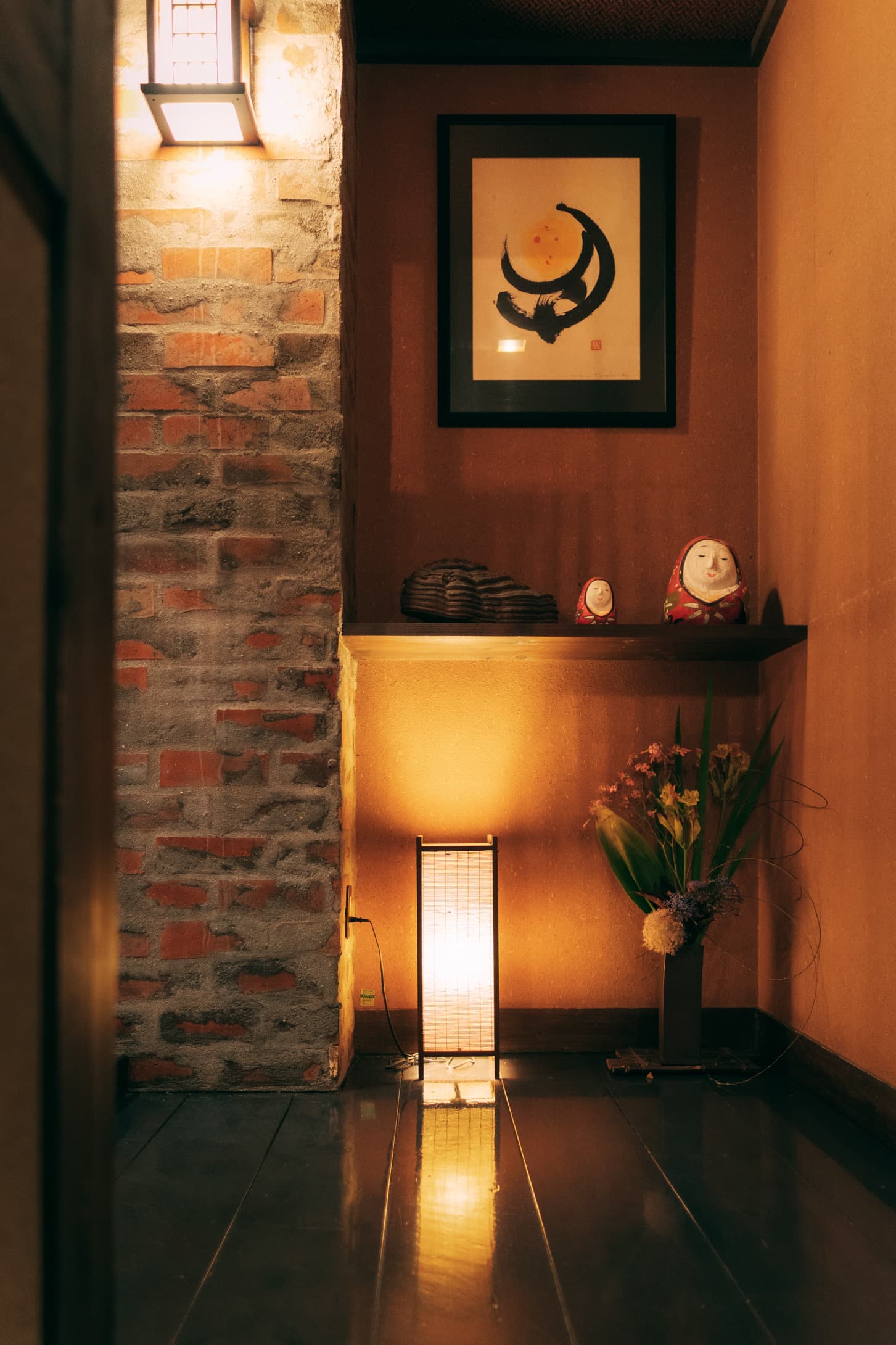 Ryokan Yamanoyu alcove detail with brick wall, ink-wash scroll, andon lamp and flower arrangement
