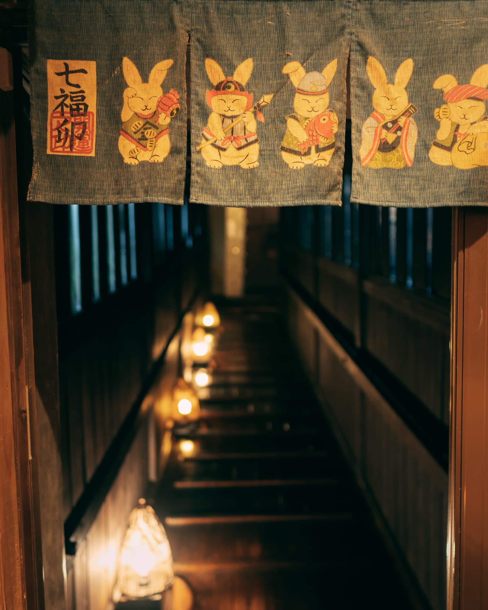 Ryokan Yamanoyu lantern-lit interior corridor with Seven Lucky Gods rabbit noren curtain