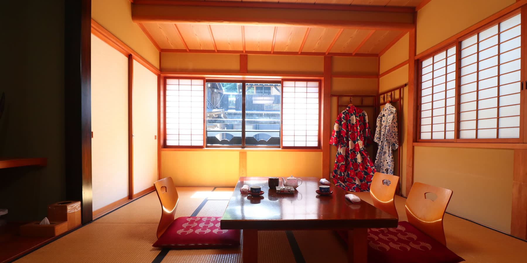 Tatami guest room with low table and yukata robes overlooking Ginzan Onsen's gas-lamp street at Yanadaya